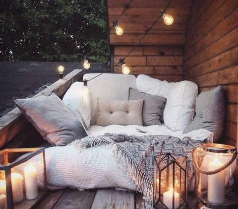 Canapé d'extérieur avec beaucoup de coussins et un très beau plaid