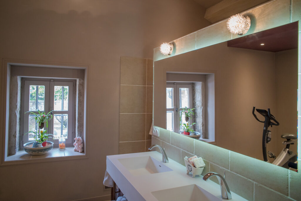 La lumière naturelle rentre par la fenêtre et vient se renvoyer dans le miroir au dessus de la vasque pour un meilleur éclairage de la salle de bain